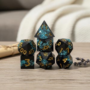 May include: A set of seven polyhedral dice for role-playing games. The dice are black with gold numerals and a teal and blue marbled effect. Includes a d4, d6, d8, d10, d12, d20, and a percentile die.