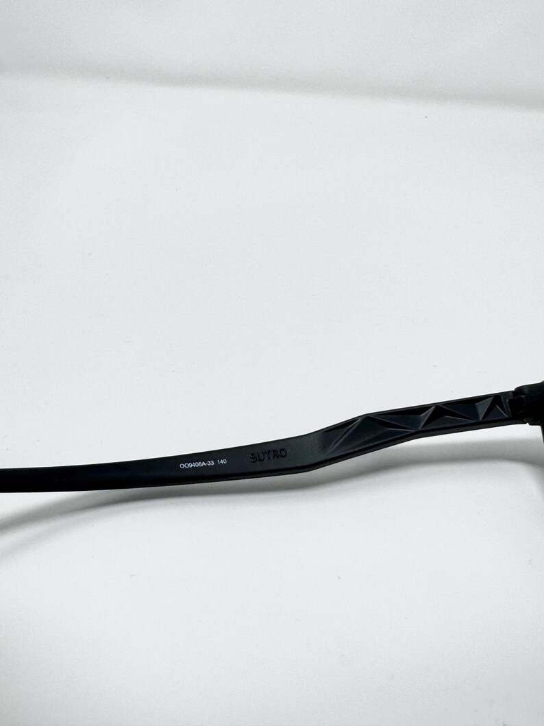 May include: Black eyeglasses arm with the brand name "SUTRO" printed on the side. The arm has a geometric design and the model number "DC0406A-33 140" is also visible.