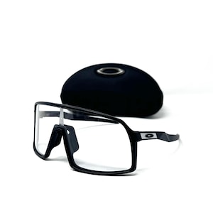 May include: Black framed sunglasses with clear lenses and a black case. The sunglasses have a modern, sporty design with a rectangular shape. The case is oval and has a silver emblem.