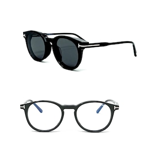 Peut inclure: Deux paires de lunettes à monture noire. Une paire est des lunettes de soleil avec des verres foncés, et l'autre est des lunettes de vue avec des verres clairs. Les deux paires ont un design de monture ronde avec un accent blanc distinctif sur les branches.