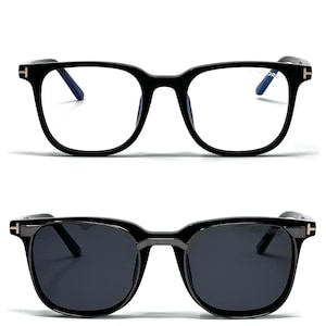 Peut inclure: Deux paires de lunettes à monture noire. La paire supérieure a des verres transparents, tandis que la paire inférieure a des verres foncés et teintés. Les deux paires ont une forme carrée et la marque "TOM FORD" est visible sur les branches.