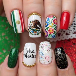 May include: A set of manicured nails with various designs. One nail features the Mexican flag, while others display the Mexican coat of arms, floral patterns, and fireworks. The phrase "Viva México" is also featured. Colors include red, green, white, gold, and black.