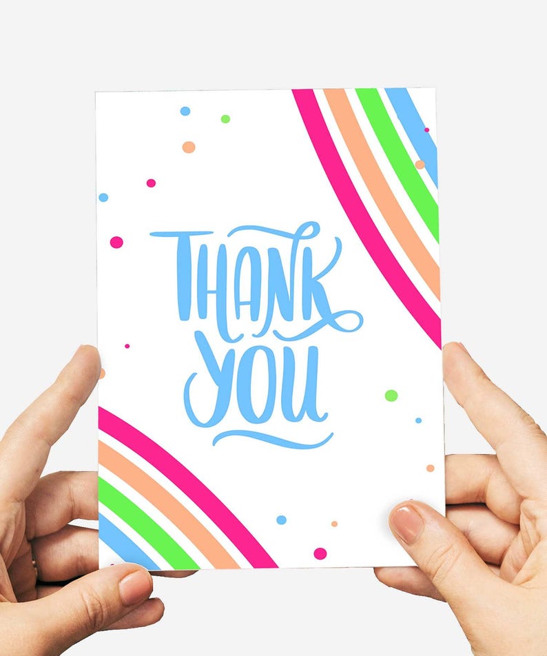 May include: A white card with the words "THANK YOU" in blue script. The card has a rainbow design with pink, orange, green, and blue stripes. Small colorful dots are scattered around the card.