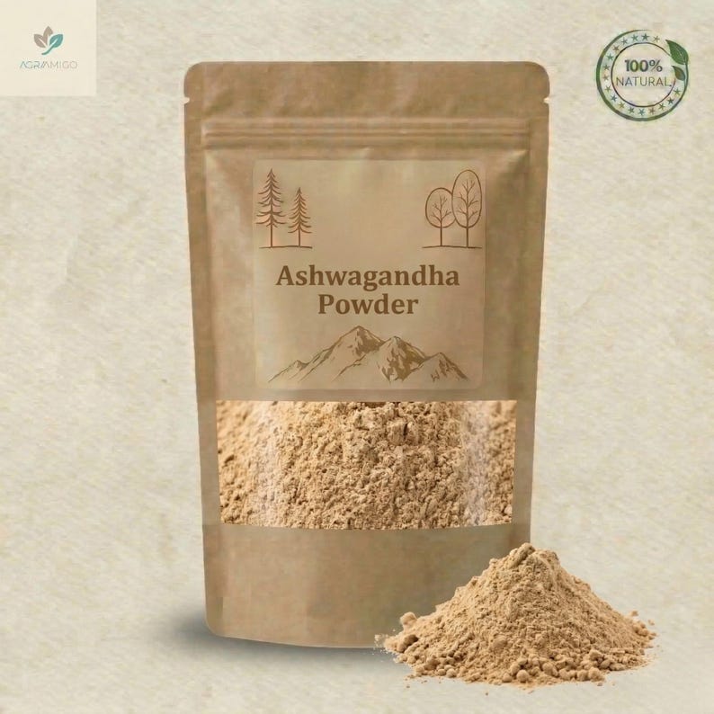 Peut inclure: Un sac en papier brun contenant de la poudre d'Ashwagandha, avec une fen&ecirc;tre transparente r&eacute;v&eacute;lant la poudre. L'&eacute;tiquette porte le texte "Ashwagandha Powder" avec une illustration de montagne et des graphiques d'arbres.