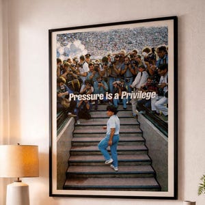 May include: Framed art print featuring a crowd of photographers and a person walking up stairs. The text "Pressure is a Privilege" is displayed. The image has a vintage aesthetic, with a focus on the subject and the surrounding environment.