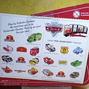 May include: A red and white package featuring various miniature toy cars from the "Cars" movie franchise. The package includes images of Lightning McQueen, Sally, and other characters. Text on the package reads "Collect MINI ADVENTURES vehicles!" and "Stop by Radiator Springs".