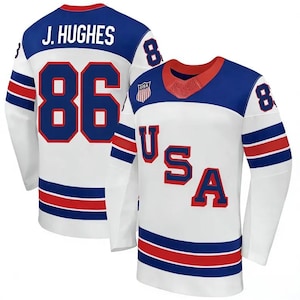 May include: White hockey jersey with blue and red accents. Features the name "J. HUGHES" and the number "86" on the back. The front displays "USA" in red letters. The jersey has a red and blue collar and blue stripes on the sleeves.