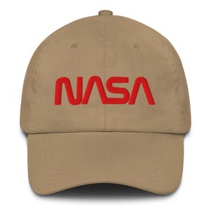 Peut inclure: Casquette de baseball beige avec le logo NASA rouge brodé sur le devant. La casquette a une visière incurvée et une sangle réglable à l'arrière. Fabriquée en tissu doux et résistant.
