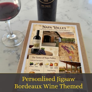 May include: A rectangular jigsaw puzzle box featuring a Napa Valley wine theme, with text reading Napa Valley, Lucy & John's California Wine Tasting Weekend, and The Tastes of Napa Valley, alongside a wine glass and a bottle of red wine.