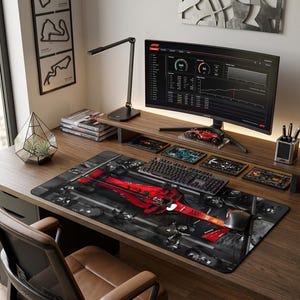 Può includere: Una moderna postazione di lavoro con un grande monitor curvo che mostra dati, una tastiera nera e un mouse. Un ampio tappetino per mouse con un design di auto da corsa rossa domina la scrivania. Altri elementi includono una lampada da scrivania, un portapenne e opere d'arte decorative.