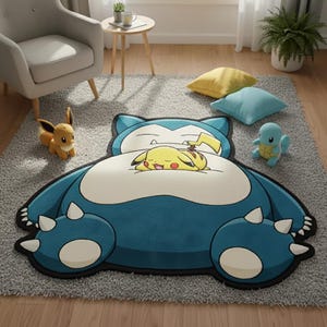 May include: A large, shaped area rug featuring a blue and cream Snorlax character with a yellow Pikachu character resting on its stomach. The rug is positioned on a gray carpeted floor, surrounded by small plush toys including Eevee and Squirtle.