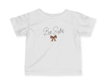 Camiseta infantil de punto fino, con la inscripción "Hermana mayor" y un lazo de leopardo, perfecta para anunciar el embarazo o para fotos familiares.