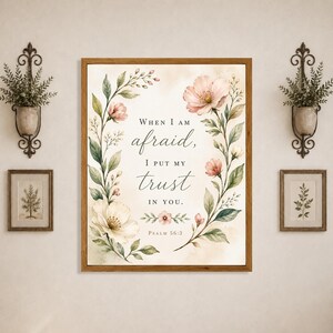 Peut inclure: Une impression murale rectangulaire dans un cadre en bois avec le texte When I am afraid, I put my trust in you. Psalm 56:3. Le motif est orné de fleurs roses et de feuilles vertes de style aquarelle disposées en couronne florale.