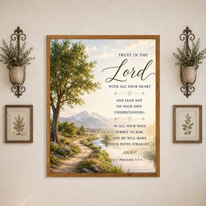 May include: A rectangular wall art piece in a wooden frame featuring a landscape of a dirt path, a river, and mountains. The text reads: Trust in the Lord with all your heart and lean not on your own understanding; in all your ways submit to him, and he will make your paths straight. Proverbs 3:5-6.