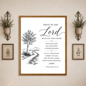 Puede incluir: Un cuadro decorativo enmarcado que presenta una ilustración en tinta negra y blanca de un árbol y un camino a la izquierda, con el texto 'TRUST IN THE LORD WITH ALL YOUR HEART AND LEAN NOT ON YOUR OWN UNDERSTANDING; IN ALL YOUR WAYS SUBMIT TO HIM, AND HE WILL MAKE YOUR PATHS STRAIGHT. - PROVERBS 3:5-6' a la derecha.