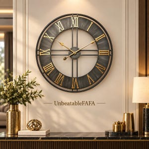 Puede incluir: Un gran reloj de pared circular con un marco gris carbón oscuro de acabado cepillado y números romanos dorados. El reloj tiene manecillas doradas finas y un eje central. El texto UnbeatableFAFA está impreso debajo de la esfera del reloj.