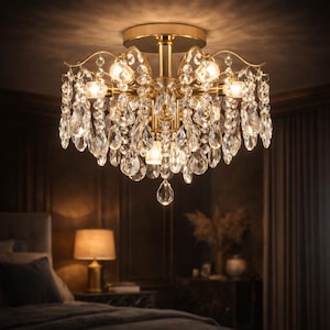 Op de afbeelding: Een goudkleurige kroonluchter met meerdere lampen en hangende kristallen druppels. De armatuur is aan het plafond bevestigd en verlicht een slaapkamer. De kristallen reflecteren licht en creëren een sprankelend effect.