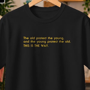 May include: Black t-shirt with yellow text: "The old protect the young, and the young protect the old. THIS IS THE WAY." The tee is displayed on a wooden hanger.