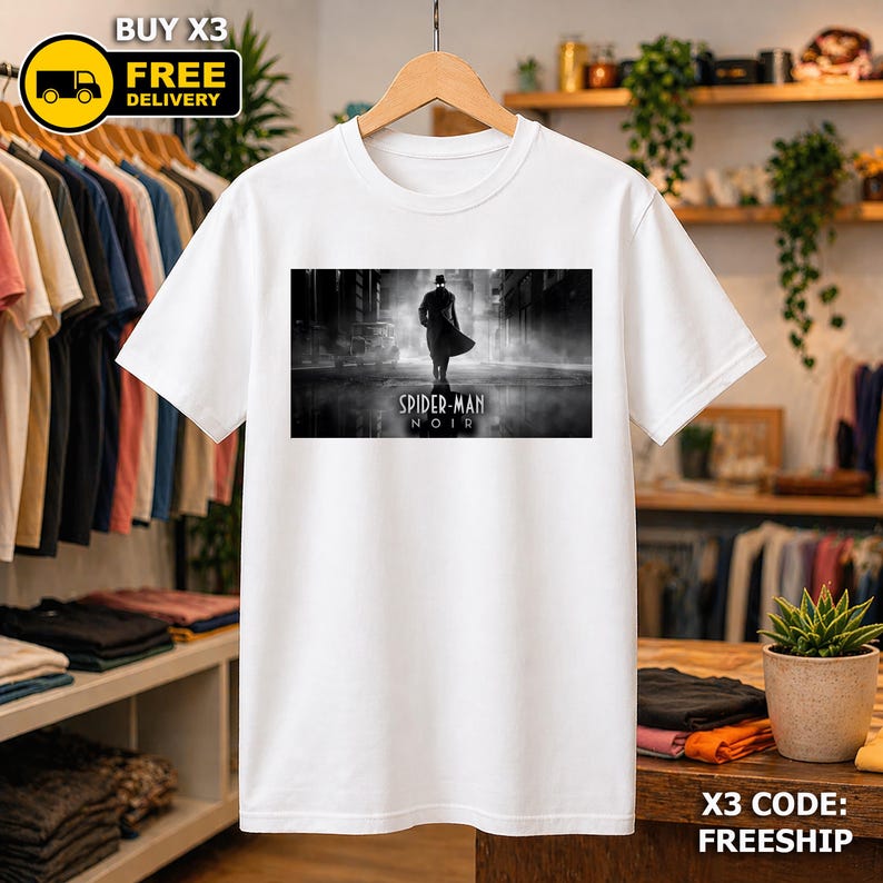 May include: A white short-sleeved t-shirt featuring a rectangular black and white graphic print on the chest. The graphic depicts a silhouetted figure in a trench coat and hat standing on a wet street with the text Spider-Man Noir below it.