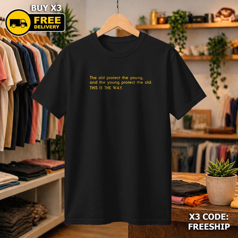 May include: Black t-shirt with yellow text: "The old protect the young, and the young protect the old. THIS IS THE WAY." The tee is displayed on a wooden hanger.