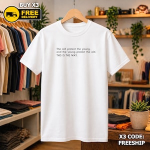 May include: A white t-shirt featuring the text "The old protect the young, and the young protect the old. THIS IS THE WAY." in black. The shirt hangs on a wooden hanger. A "BUY X3 FREE DELIVERY" graphic is in the top left corner.