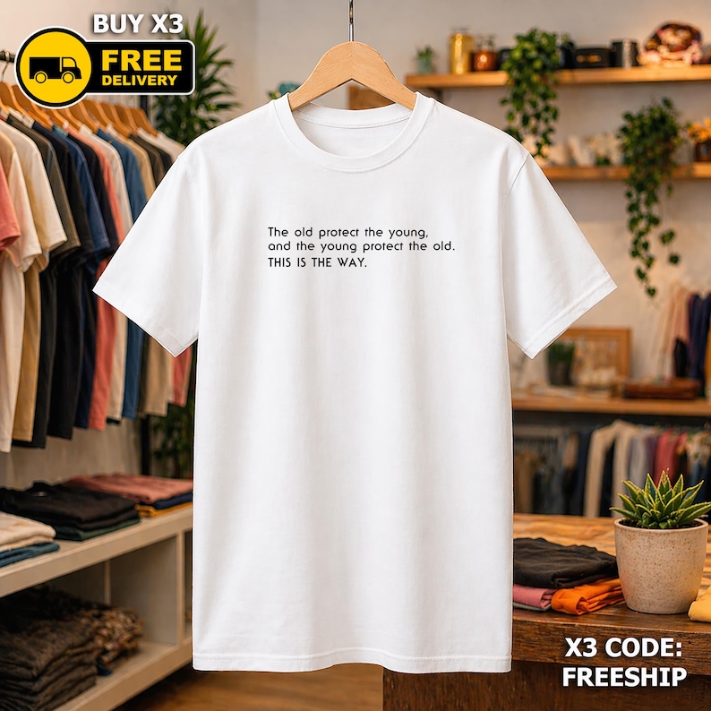 May include: A white t-shirt featuring the text "The old protect the young, and the young protect the old. THIS IS THE WAY." in black. The shirt hangs on a wooden hanger. A "BUY X3 FREE DELIVERY" graphic is in the top left corner.