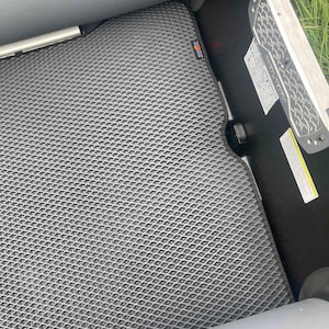 K&ouml;nnte beinhalten: Eine dunkelgraue Bodenmatte mit rautenf&ouml;rmigem Gittermuster, die im Inneren eines Bootes installiert ist. Die Matte verf&uuml;gt &uuml;ber ein kleines rechteckiges Etikett mit dem Text EVAWAY. Eine schwarze Seitenwand mit wei&szlig;em Aufkleber ist sichtbar.
