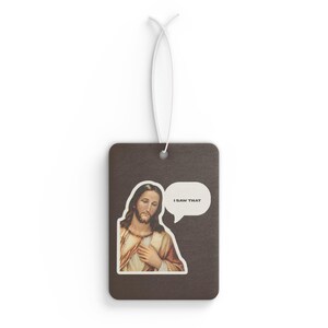 May include: A rectangular brown air freshener featuring a printed illustration of Jesus with a speech bubble containing the text I SAW THAT. The item includes a white elastic string attached through a hole at the top for hanging purposes.