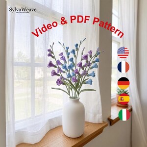 May include: A white ceramic vase holding a bouquet of crocheted flowers in shades of purple and blue. The text "Video & PDF Pattern" is in red. The SylvaWeave crochet pattern logo is in the top left corner.