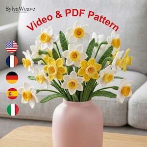 May include: A bouquet of crocheted daffodils in a pink vase. The flowers are white and yellow with green stems and leaves. The text "Video & PDF Pattern" is in red above the flowers. The SylvaWeave logo is in the upper left corner.