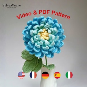 Könnte beinhalten: Eine gehäkelte Blume mit blauen und hellblauen Blütenblättern und einem gelben Zentrum, mit grünen Blättern an einem Stiel in einer weißen Vase. Der Text lautet SylvaWeave Crochet Pattern und Video & PDF Pattern. Fünf kreisförmige Nationalflaggen.