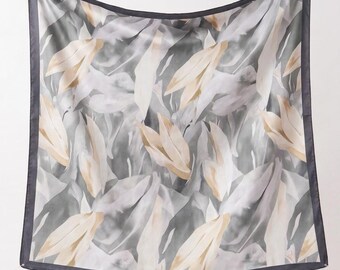 May include: A square scarf featuring a repeating pattern of abstract leaves in shades of cream, light gray, and dark charcoal. The fabric has a smooth finish and is framed by a solid dark charcoal border along all four edges of the square piece.