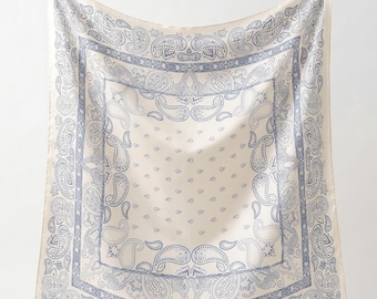 May include: A square scarf featuring a cream-colored base with a blue paisley pattern. The design includes a central field of small paisley motifs surrounded by a wide border of larger, intricate paisley shapes and geometric line details.