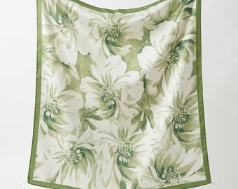 May include: A square scarf featuring a white background with a repeating pattern of large, sage green floral blossoms. The scarf is finished with a solid sage green border along all four edges, creating a cohesive and botanical appearance.