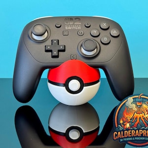 Może przedstawiać: Czarny kontroler Nintendo Switch Pro spoczywający na czerwono-biało-czarnej Poké Ball. Kontroler ma białe akcenty i napis "Nintendo Switch" na górze. Kolorowa naklejka z napisem "CALDERAPRINTING" znajduje się w prawym dolnym rogu.