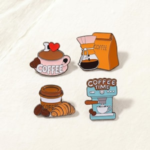 Peut inclure: Ensemble de quatre broches émaillées sur le thème du café. Les motifs comprennent une tasse à café rose avec le texte "COFFEE", une cafetière à verser, un sac de café, un gobelet à emporter avec un croissant et une machine à café avec le texte "COFFEE TIME".