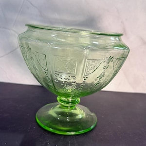 Peut inclure: Un saladier en verre vert avec une base large et hexagonale et une base ronde. Le saladier présente des motifs géométriques et floraux en relief. Le verre a une légère teinte verdâtre, et le saladier est probablement vintage.