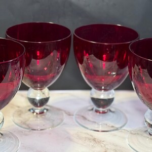 Set van vier vintage robijnrode glazen bekers met bolvormige knopstelen.