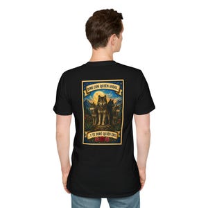 May include: A black short-sleeved t-shirt featuring a rectangular graphic on the back. The print displays three wolves in a mountain landscape under a full moon, framed by banners with the text "DIME CON QUIÉN ANDAS..." and "Y TE DIRÉ QUIÉN ERES."