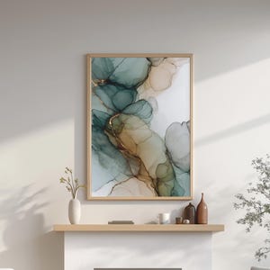 May include: A framed abstract art print with teal, gold, and beige tones hangs above a white fireplace. Two light wood armchairs with white cushions sit on a white rug. A vase and decorative bottles are on the mantel.