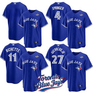 May include: Royal blue baseball jerseys with the Toronto Blue Jays logo and player names and numbers. The jerseys have white detailing on the sleeves and collar. Player names include Springer, Bichette, and Guerrero Jr.