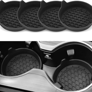 May include: Set of four black car cup holder coasters with a textured, geometric pattern. Each coaster has a small tab for easy removal. The image also shows the coasters in use inside a car's cup holders.