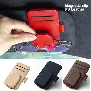 May include: Red PU leather magnetic clip for car sun visor, holding eyeglasses. The clip has a small pocket for cards. Additional clips in beige, black, and brown are also shown. Text on the image reads: Magnetic clip PU Leather.