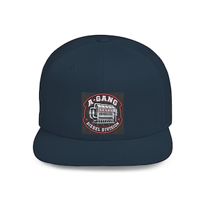 May include: A navy blue baseball cap featuring a central graphic patch. The patch displays a detailed illustration of a diesel engine with the text A-GANG DIESEL DIVISION in white and red lettering, framed by a red border and two small red stars.
