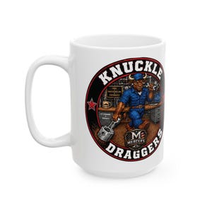 May include: A white ceramic mug featuring a circular graphic of a bull character wearing a blue work shirt and cap, holding a metal piston. The text reads KNUCKLE DRAGGERS and MERCER'S MARCH ART, with a workshop background including tools and a laptop.