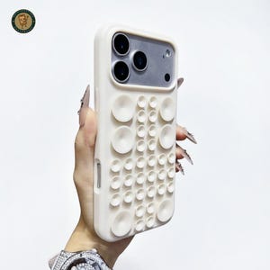 May include: Off-white phone case with a unique, textured design featuring a pattern of raised circles. The case has a camera cutout and a smooth, matte finish. The case is designed to protect the phone.