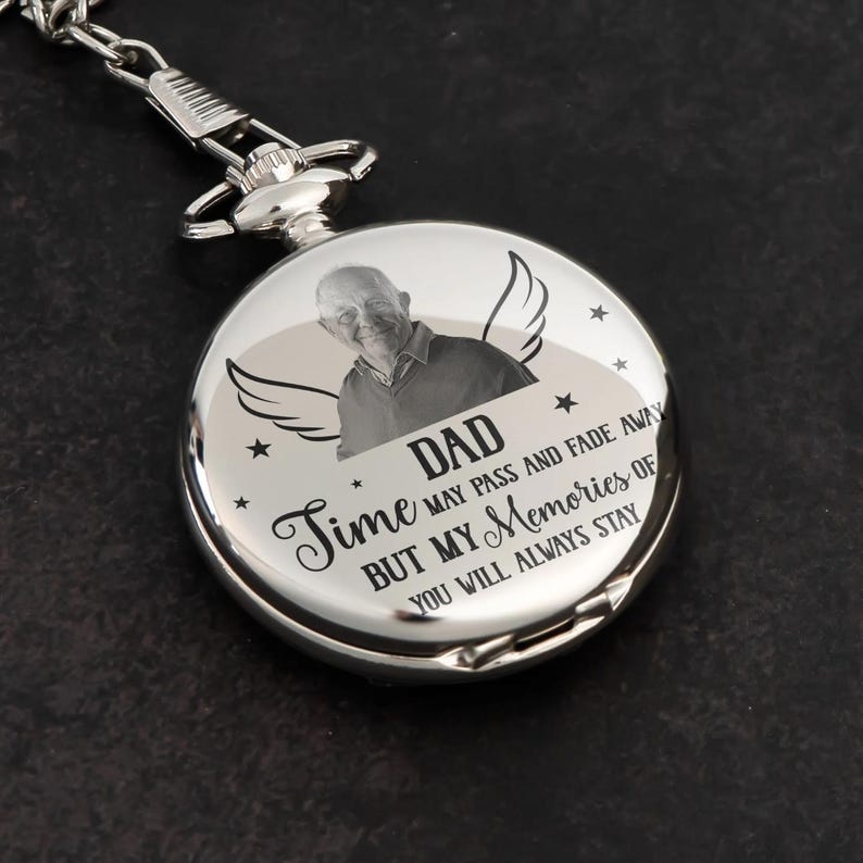 May include: A silver pocket watch with a chain. The watch face features a photo of a man, the word "DAD", angel wings, and the text "Time may pass and fade away but my memories of you will always stay."
