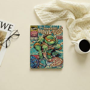 May include: A rectangular notebook featuring a comic book cover titled The Amazing Ninja-Dude. The cover art depicts a green turtle character with an orange mask eating a pepperoni pizza with cheese strings, and text reading It's Pizza Time.