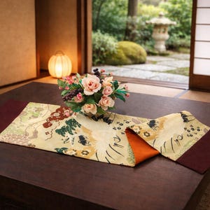 May include: A low, dark brown wooden table with a decorative runner and a floral arrangement. The runner has a cream-colored background with a colorful pattern and burgundy borders. A bouquet of pink roses and berries sits atop the runner.