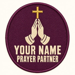 May include: A circular embroidered patch with a deep purple background. The design features a pair of light-colored hands pressed together in prayer beneath a gold cross. The text "YOUR NAME PRAYER PARTNER" is stitched in light-colored capital letters.